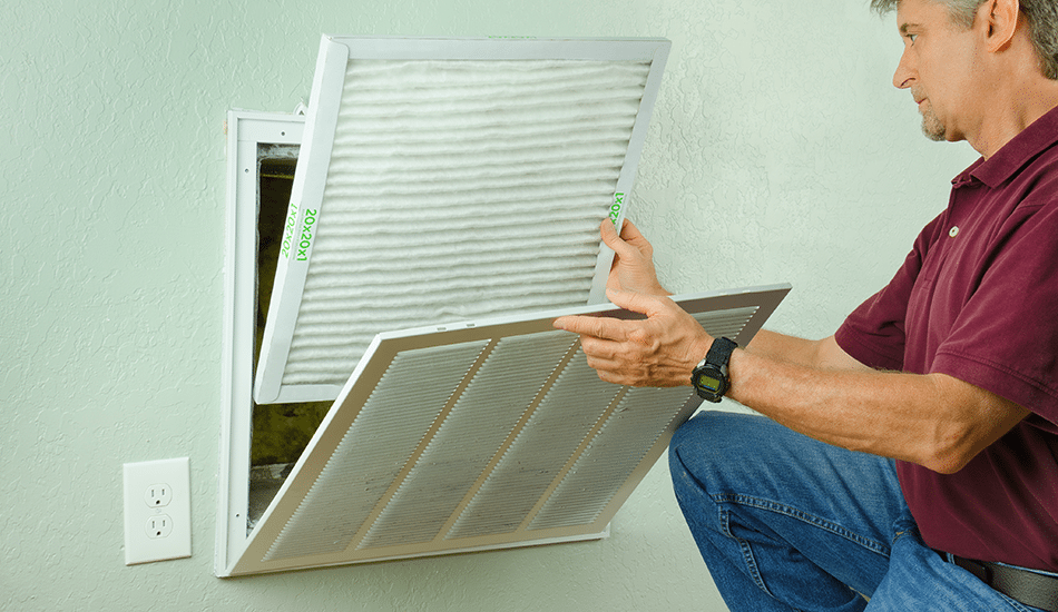 Man changing air filter | Stiles Heating, Cooling, & Plumbing