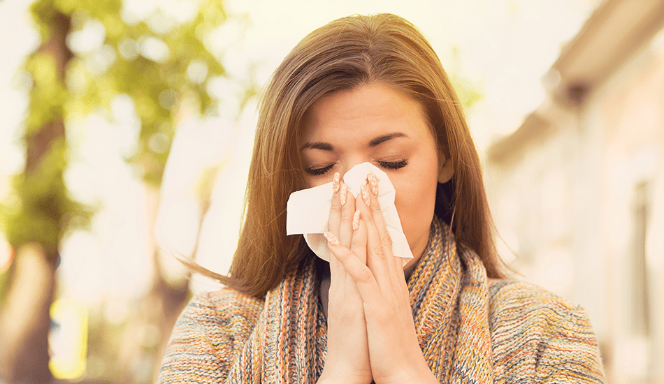 Woman sneezing into tissue | Stiles Heating, Cooling, & Plumbing